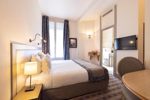 a hotel room with a bed and a table with a lamp at Hotel Residence Foch in Paris