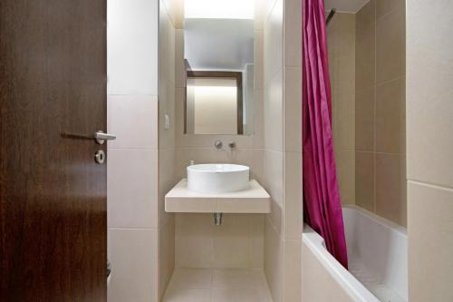 a bathroom with a sink and a pink shower curtain at Apartamento Herdade dos Salgados in Guia