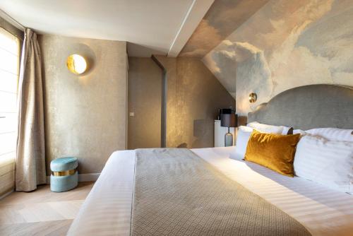 a bedroom with a large bed with a painting on the wall at Hotel Residence Foch in Paris