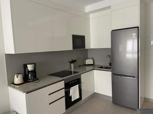 a kitchen with white cabinets and a stainless steel refrigerator at Castelar Rooms in Las Palmas de Gran Canaria
