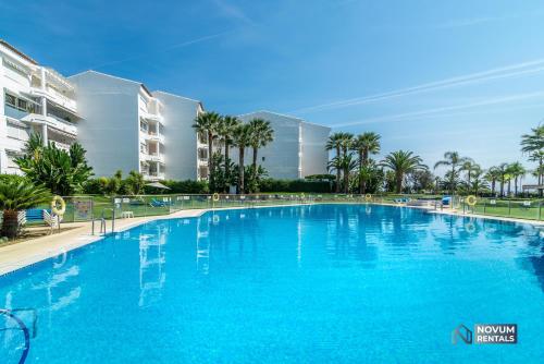 una gran piscina azul con palmeras y edificios en Lovely 1 BDRM Rental Unit w/ Pool in Puerto Banús, en Marbella
