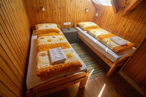 two twin beds in a room with wooden walls at Radics Panzió Étterem és Pihenő Központ in Letenye