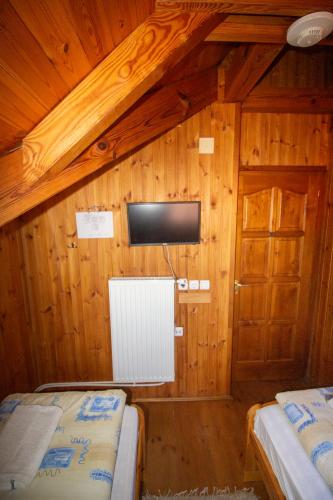 a room with two beds and a tv on a wall at Radics Panzió Étterem és Pihenő Központ in Letenye