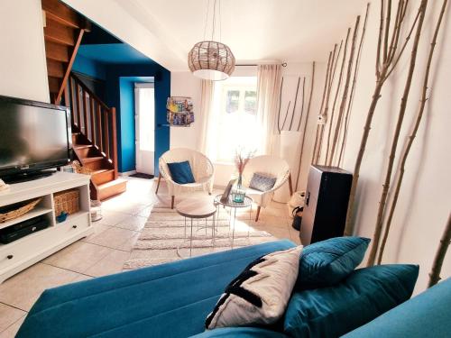 een woonkamer met een blauwe bank en stoelen bij La Tiny proche lac et forêt in Sillé-le-Guillaume