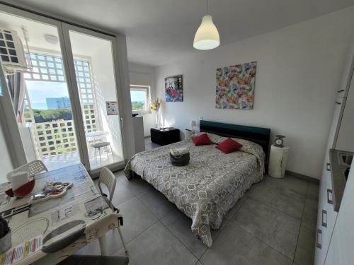a bedroom with a bed and a table and windows at Rosato Sea View Apartment in Lignano Sabbiadoro