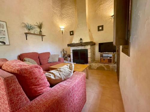 a living room with two red couches and a television at Casas Amarillas. Finca el Campillo in Blanca