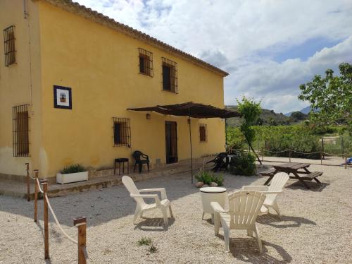 a group of chairs and an umbrella in front of a building at Casas Amarillas. Finca el Campillo in Blanca
