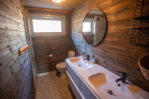 uma casa de banho com um lavatório, um WC e um espelho. em Fidjeland Holiday Home em Sinnes