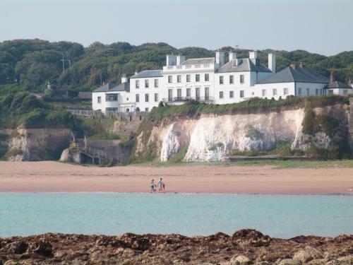 two people standing on the beach in front of a house at Broadstairs Beach Holiday Apartments, opposite Kingsgate Bay with a parking space in Broadstairs