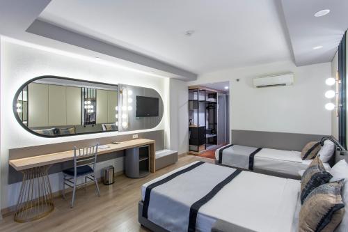 Un dormitorio con dos camas y un escritorio y un espejo. en Eftalia Aqua Resort, en Konaklı