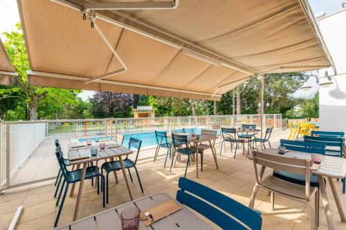 a patio with tables and chairs and a swimming pool at B&B HOTEL Lyon Nord 4 étoiles in Dardilly