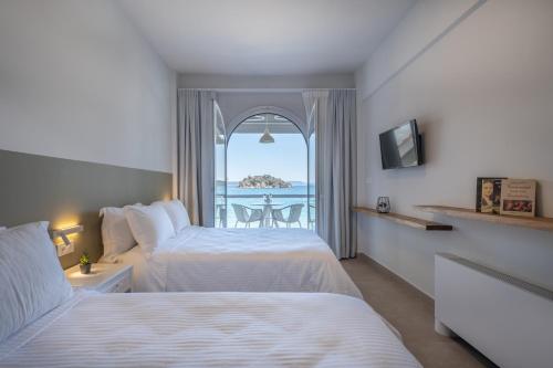 a bedroom with two beds and a view of the ocean at Nelly's Apartments in Tolo