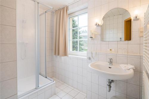 a white bathroom with a sink and a shower at Landhaus Purschenstein in Neuhausen