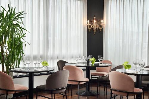 a dining room with tables and chairs and a chandelier at Hotel President in Viareggio