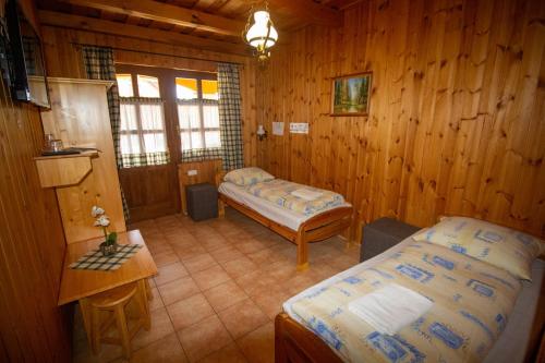 a bedroom with two beds in a wooden room at Radics Panzió Étterem és Pihenő Központ in Letenye