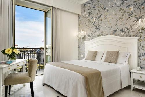 a bedroom with a bed and a desk and a window at Hotel President in Viareggio