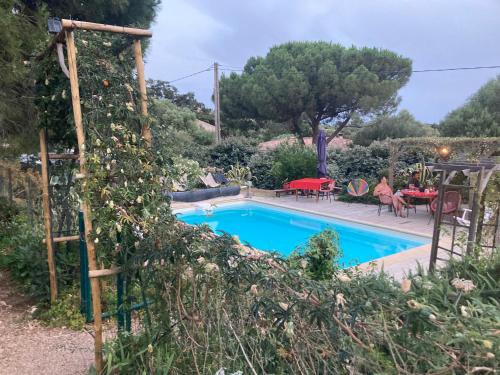 een zwembad in een tuin met een tafel en stoelen bij chambre double avec salle de bain privée in Monacia-dʼAullène