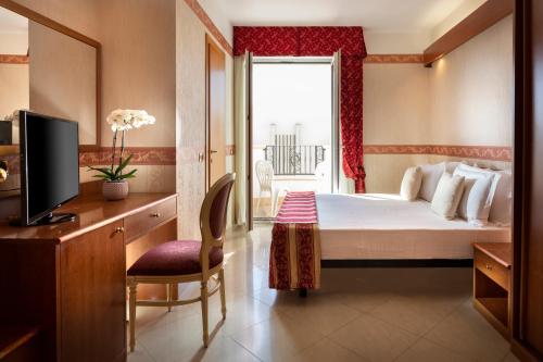 a hotel room with a bed and a television at Hotel Gallia Palace in Rimini