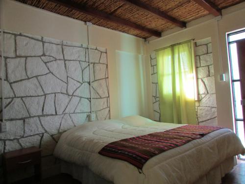 a bedroom with a bed with a stone wall at Altos del Lascar in Toconao