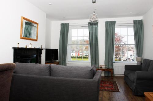a living room with a couch and two windows at 2 Yr Hen Fanc in Aberaeron