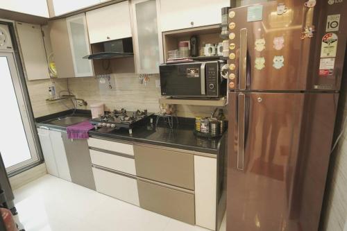 a kitchen with a refrigerator and a microwave at CITY HOMES ORCHID APARTMENT in Mumbai