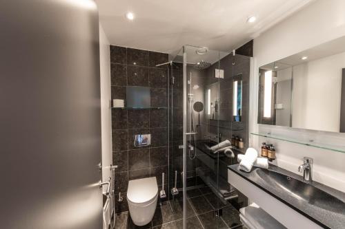 a bathroom with a toilet and a sink and a mirror at Best Western Plus Hotel Ilulissat in Ilulissat