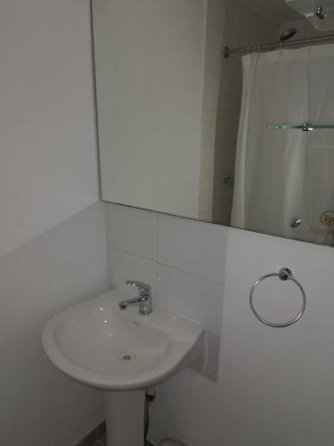 a white bathroom with a sink and a mirror at Zigal hotel in Antofagasta