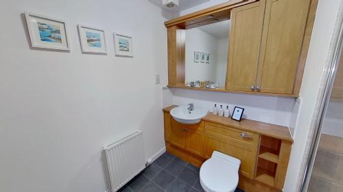 La salle de bains est pourvue de toilettes, d'un lavabo et d'un miroir. dans l'établissement Orange Apartments Bothwell Road, à Aberdeen
