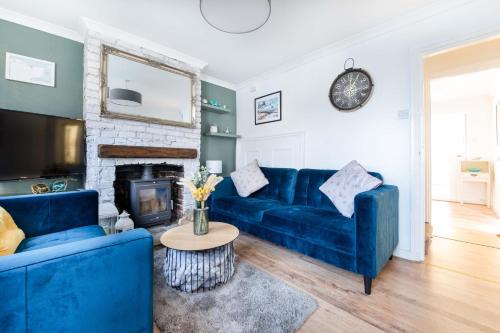 a living room with a blue couch and a fireplace at Sprite Cottage, in the heart of Whitstable in Whitstable