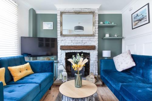 a blue couch in a living room with a fireplace at Sprite Cottage, in the heart of Whitstable in Whitstable