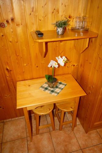a wooden table with a vase of flowers on it at Radics Panzió Étterem és Pihenő Központ in Letenye