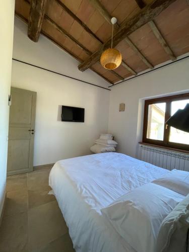a bedroom with a large white bed and a toilet at Maremma Country Chic (il Gelsomino) in Sovana