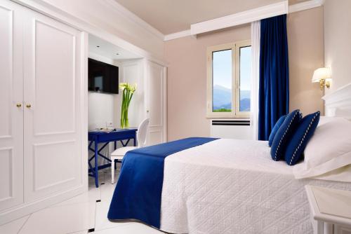 a white bedroom with a blue and white bed and a table at Hotel President in Viareggio
