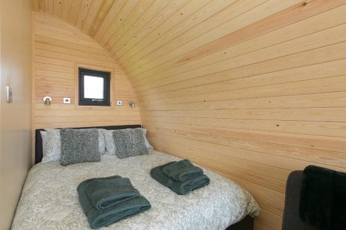 a bed in a room with a wooden wall at Green Fields in Penzance