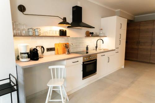 a kitchen with white cabinets and a sink and a stool at Familienapartment Reifnitz in Maria Wörth