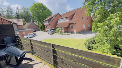 a house with a fence and a bench on a porch at Hotel Schnehagen in Bad Fallingbostel
