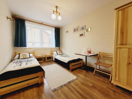 een kamer met twee bedden, een tafel en een raam bij Daglezja in Przyborów