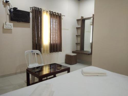 a bedroom with a bed and a mirror and a chair at Hotel Krishna Exotica in Ahmadnagar