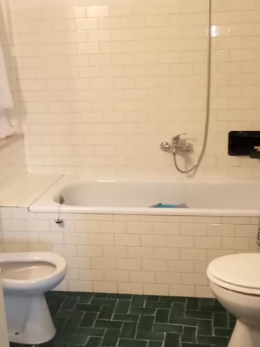 a white bathroom with a tub and a toilet at Marina's house in Imperia