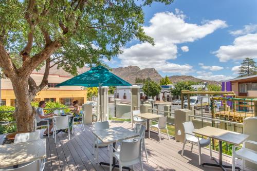 eine Terrasse mit Tischen und Stühlen und einem Baum in der Unterkunft Montagu Country Hotel in Montagu