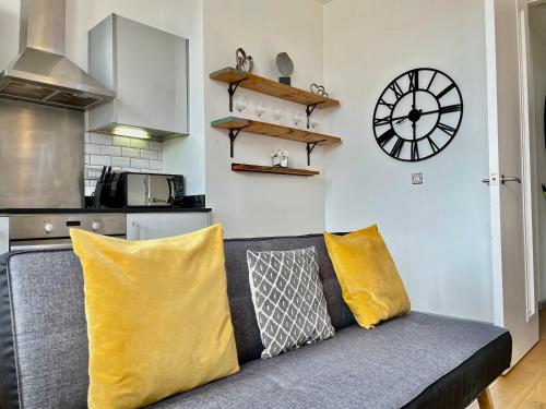 a living room with a couch and a clock on the wall at Victorian Factory Apartment with 2 Bedrooms in Bristol
