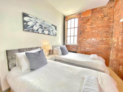 a bedroom with two beds and a brick wall at Victorian Factory Apartment with 2 Bedrooms in Bristol