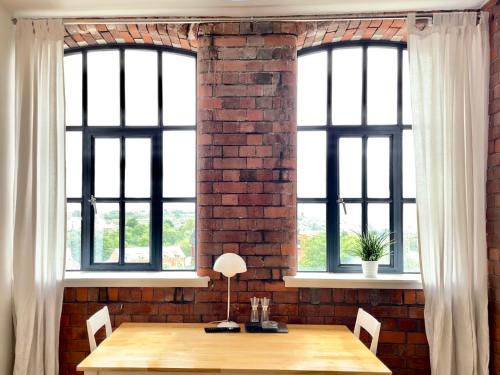 a brick wall and a table with two windows at Victorian Factory Apartment with 2 Bedrooms in Bristol