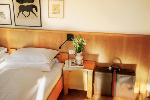 a bedroom with a bed and a side table with flowers at Weisses Rössl in Caldaro