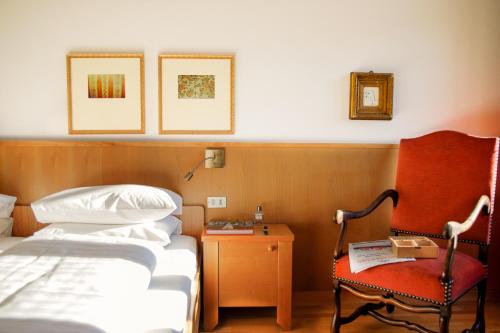 a hotel room with a bed and a chair at Weisses Rössl in Caldaro