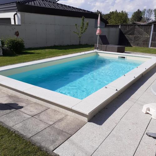 a swimming pool with blue water in a yard at Reitbergs Nest in Eugendorf