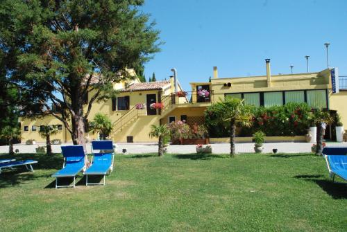 a group of chairs sitting in the grass in front of a house at Camping Village Mar y Sierra in San Costanzo