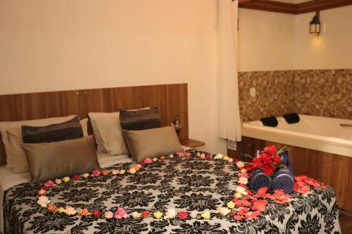 Una cama grande con flores en una habitación en Arraialferias Suites, en Arraial do Cabo