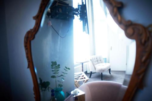 a mirror in a room with a chair and a table at Embankment Hotel in Bedford