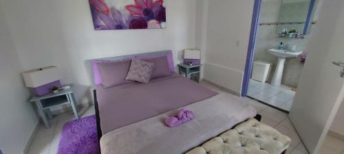 a small bedroom with a purple bed and a bathroom at Villa Raven`s Paradise (Lavender) in Willemstad